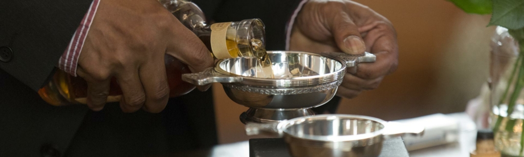 Mann portioniert Whisky-in schottischem Quaich für Zeremonie.