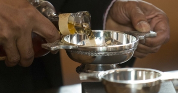 Mann portioniert Whisky-in schottischem Quaich für Zeremonie.